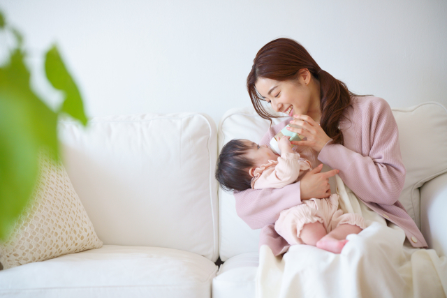 笑顔でミルクをあげる女性