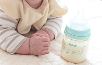 赤ちゃんの隣にある哺乳瓶
